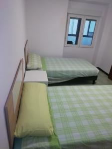 two twin beds in a room with a window at casa de tres habitaciones con parking bajo la casa in Villajoyosa