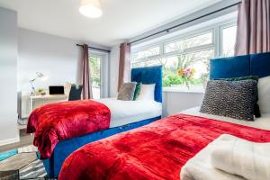 two beds with red and blue covers in a bedroom at Simba Stays - Contractors, Relocators , Families, Wi-Fi, Free Parking in Hemel Hempstead