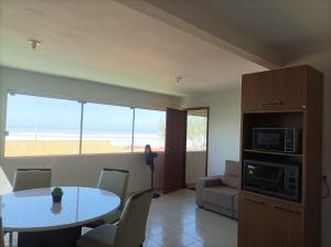 a living room with a table and a microwave at AP Beira mar in Laranjal