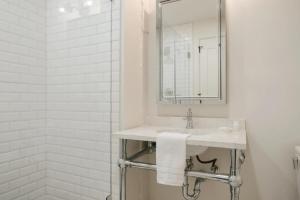 a white bathroom with a sink and a mirror at La Luz in San Antonio