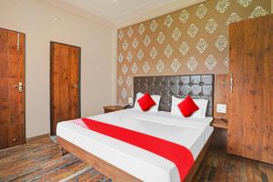 1 dormitorio con 1 cama grande con almohadas rojas en OYO Flagship MH Inn en Varanasi