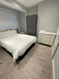 a bedroom with a white bed and a dresser at Vale NKY Apartment Rooms in London