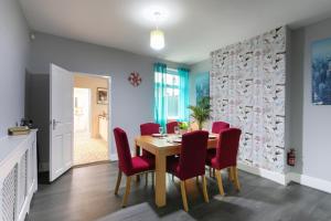 a dining room with a table and red chairs at Luxury 3BR House - Free Parking and Stunning Garden! in Nottingham