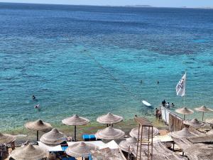 una spiaggia con ombrelloni e persone in acqua di Sharm Inn Amarein - Boutique Hotel a Sharm El Sheikh