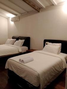 2 Betten in einem Zimmer mit weißer Bettwäsche in der Unterkunft Amara Villa in Gili Trawangan