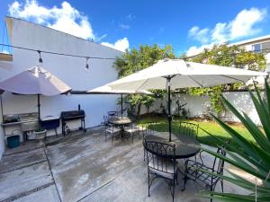 a patio with tables and chairs and an umbrella at Quetzal House in Tijuana