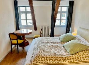 1 dormitorio con cama, mesa y ventanas en Oswald Hempel 5 Zimmermaisonette und 3 Zimmer Loftwohnung, en Zittau