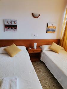 a room with two beds and a nightstand between them at apartamento Mirada I 22 ET-294PL in Es Pujols