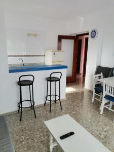 a kitchen with two bar stools and a table at apartamento Mirada I 22 ET-294PL in Es Pujols