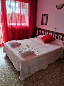 a bedroom with a large bed with red curtains at apartamento Mirada I 22 ET-294PL in Es Pujols