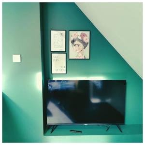 una televisione in una stanza con foto sul muro di Chalet côté montagne a Oz