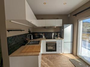 uma cozinha com armários brancos, um lavatório e um frigorífico em Le Ruisseau - Appartement 8P em Theux