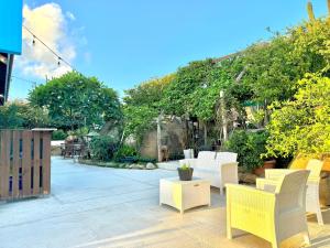 un patio con sillas blancas, mesas y árboles en Weburi Accommodation en Oranjestad