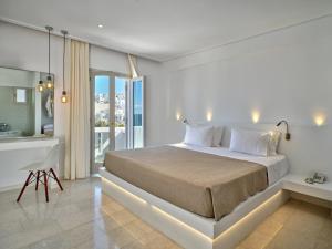 a white bedroom with a bed and a desk at Kanale's Rooms & Suites in Naousa