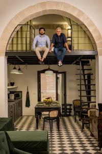 2 hommes assis sur une mezzanine dans un salon dans l'établissement Loft 900 - Home & SPA - A Timeless Luxury in Monopoli, à Monopoli