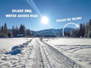 una carretera cubierta de nieve con el sol en el cielo en Szałas na szlaku en Witów
