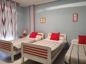 Cette chambre comprend 2 lits avec des oreillers rouges. dans l'établissement TANISHOSTALRESTAURANTE, à Riaño