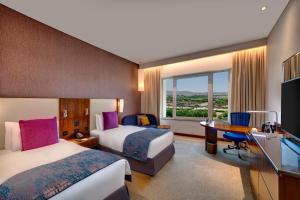 マスカットにあるCrowne Plaza Muscat OCEC, an IHG Hotelのベッド2台とデスクが備わるホテルルームです。