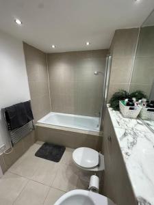 a bathroom with a tub and a toilet and a sink at Manchester's Prime - Luxurious 1-Bed Flat in Manchester