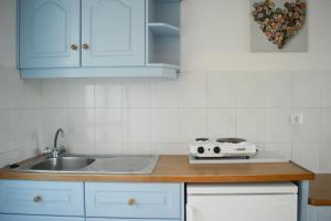 cocina con armarios blancos, fregadero y fogones en Paradise Beach Apartments en Argasi