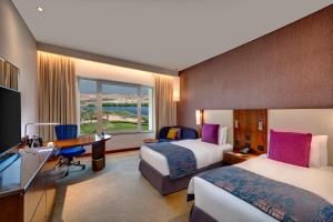 a hotel room with two beds and a desk at Crowne Plaza Muscat OCEC, an IHG Hotel in Muscat