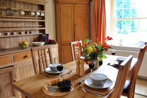 a wooden table with glasses of wine and a bowl of grapes at Finest Retreats - Ingleby Manor - Courtyard Cottage in Great Ayton