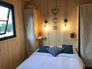 a bedroom with a bed with blue pillows on it at Camping de la côte des légendes in Brignogan-Plages