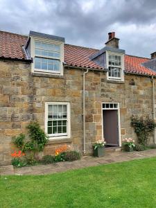 a brick house with windows and flowers in a yard at Finest Retreats - Ingleby Manor - Manor Cottage in Great Ayton