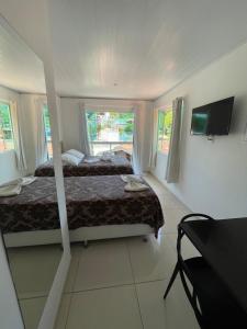 a bedroom with two beds and a television in it at Flat Morro e Casa Blanca in Morro de São Paulo