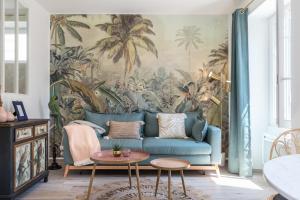 a living room with a blue couch with a tropical wallpaper at Lovely Apartment City Center Heart - AC in Nice
