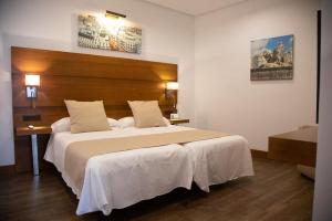 una camera con un grande letto con testiera in legno di Ferreira Hostal Boutique a Conil de la Frontera