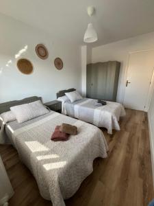 two beds in a room with white walls and wooden floors at Casa Vazan 