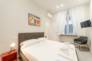 ein Schlafzimmer mit einem Bett, einem Stuhl und einem TV in der Unterkunft JOIVY The Place To Be in the Centre of Genoa in Genua