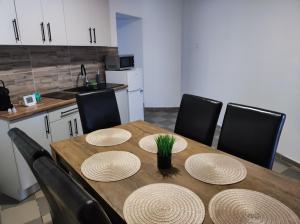 a kitchen with a wooden table and chairs with hats on it at Bástya Apartman in Tata