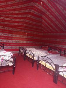 3 Betten in einem Zimmer mit roter Decke in der Unterkunft Alarb Quiet Camp in Wadi Rum