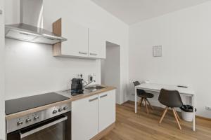 cocina con armarios blancos, mesa y sillas en StayEasy Apartments Vienna A#2, en Viena