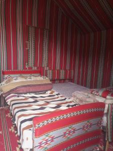 Zimmer mit 2 Betten in einem roten Zimmer in der Unterkunft Alarb Quiet Camp in Wadi Rum