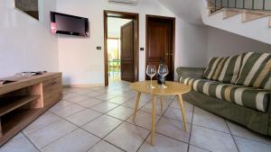 sala de estar con sofá y mesa con copas de vino en La Casetta di Teresa, en Oristano