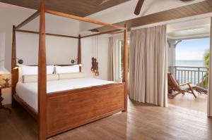 a bedroom with a four poster bed and a balcony at JW Marriott Mauritius Resort in Le Morne