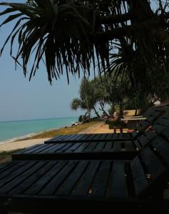 een houten bankje op een strand met uitzicht op de oceaan bij Blue Wave Beach Villa by Aaryan Group in Ambalangoda