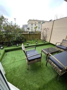 a patio with two chairs and a table on the grass at BY NEPTUNE - Appartement Disney Paris - 1 min RER in Chessy
