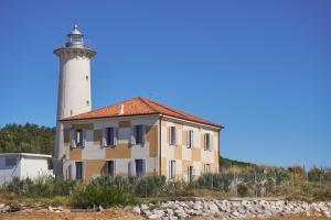 a lighthouse on the beach with a building at Luminous flat 400 m from the beach for 4 guests in Bibione