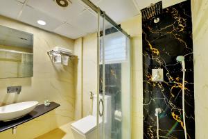 a bathroom with a glass shower and a sink at Hotel Twin Tulips HSR Layout in Bangalore