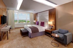um quarto de hotel com uma cama e uma cadeira em Crowne Plaza Muscat OCEC, an IHG Hotel em Mascate