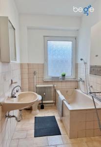 ein Bad mit einem Waschbecken, einer Badewanne und einem Fenster in der Unterkunft BEGE APARTMENTS: WORK HEAVEN in Gelsenkirchen