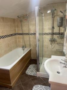 a bathroom with a shower and a tub and a sink at Rahal Compton in London