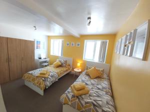 Duas camas num quarto com paredes amarelas e janelas em Beautiful Two Bedroom ground floor apartment em Swansea