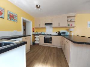 a kitchen with white cabinets and a black counter top at Beautiful Two Bedroom ground floor apartment in Swansea