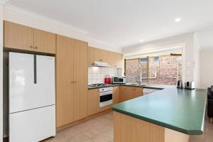 a kitchen with wooden cabinets and a green counter top at Beautiful 3 bedroom house with Corio Bay view at heart of Clifton Springs in Clifton Springs