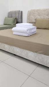 una pila de toallas blancas en una cama en Happy Chamang Guest House, en Bentong